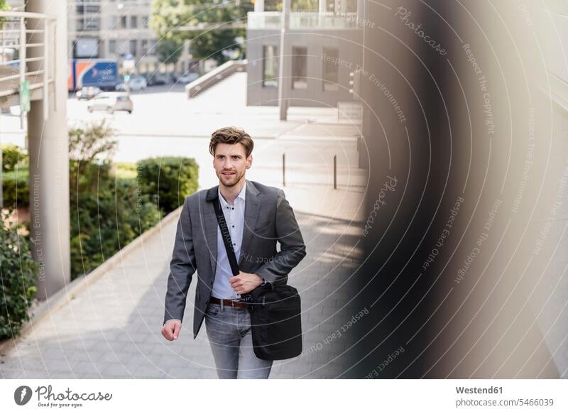 Smiling businessman with crossbody bag in the city on the move Businessman Business man Businessmen Business men town cities towns Cross body bag smiling smile
