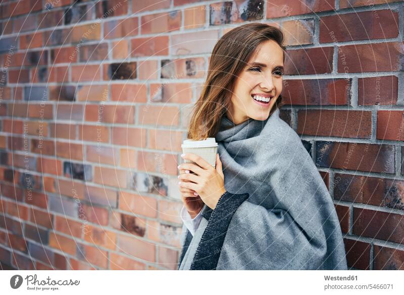 Portrair of young woman with coffee to go in front of brick wall portrait portraits brick walls Coffee Coffee to Go takeaway coffee females women Drink