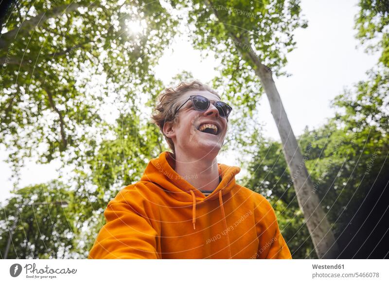 Portrait of laughing young man wearing sunglasses and orange hoodie shirt in nature Eye Glasses Eyeglasses specs spectacles Pair Of Sunglasses sun glasses