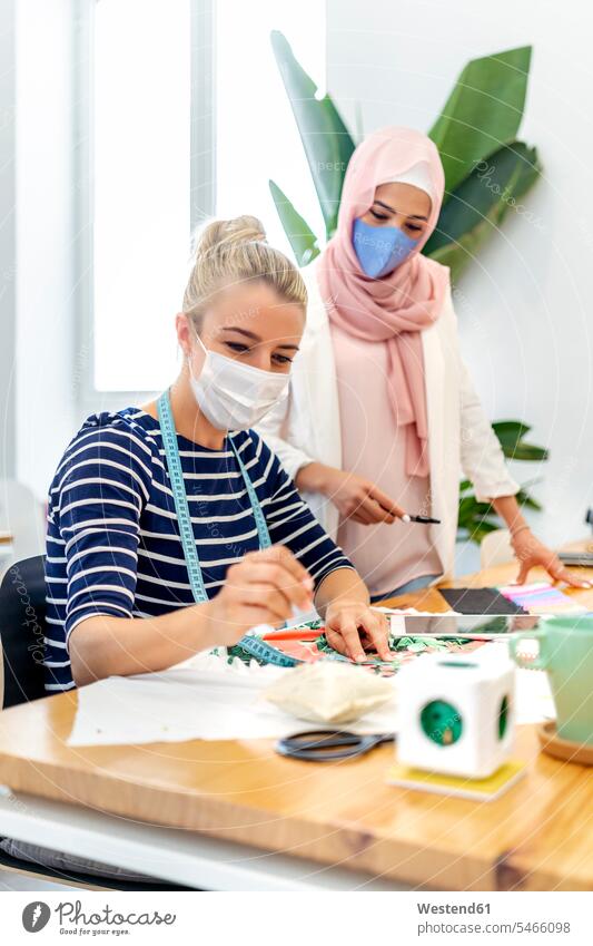 Young woman wearing face mask standing by coworker while working at office color image colour image indoors indoor shot indoor shots interior interior view