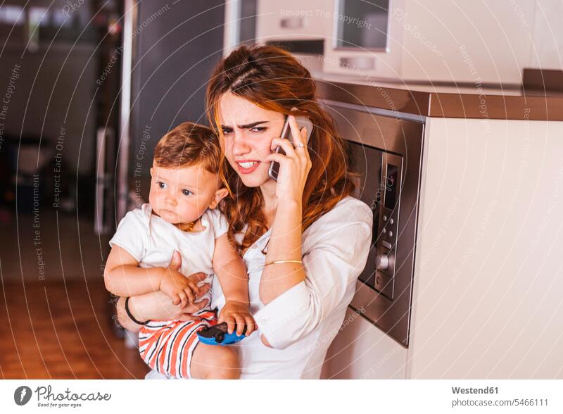 Annoyed mother with her son talking on the phone at home human human being human beings humans person persons caucasian appearance caucasian ethnicity european