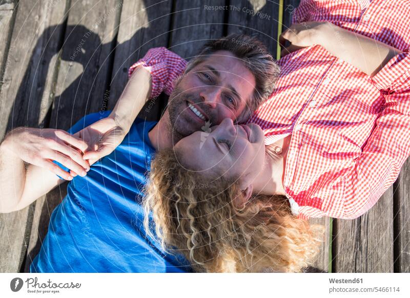 Happy affectionate couple lying on jetty laying down lie lying down twosomes partnership couples jetties happiness happy smiling smile Affection Affectionate