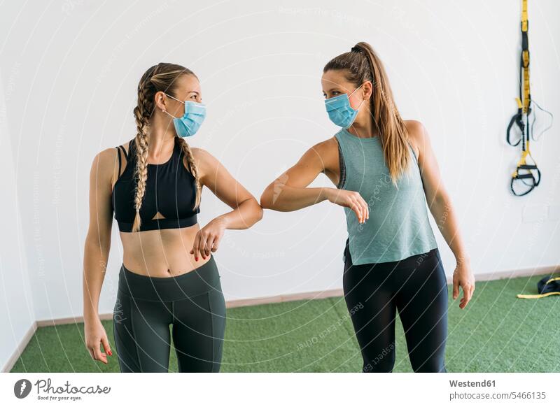 Two sporty women wearing face masks giving elbow bump at health club human human being human beings humans person persons caucasian appearance