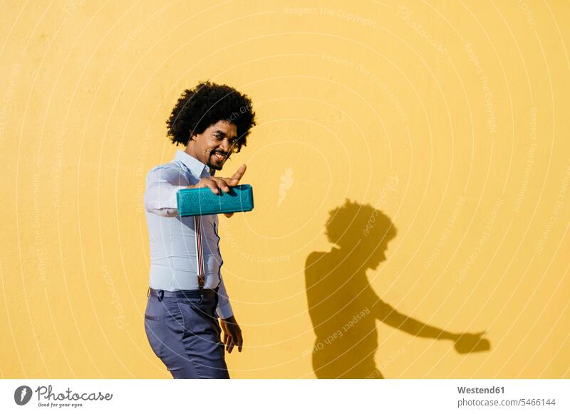 Smiling man with loudspeaker listening music and dancing in front of yellow wall men males smiling smile loudspeakers walls hearing Adults grown-ups grownups