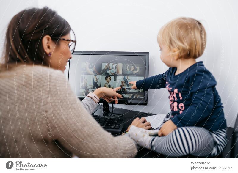Mother with little daughter sitting on desk looking at computer screen Seated home at home eyeing mother mommy mothers ma mummy mama daughters Computer Monitor