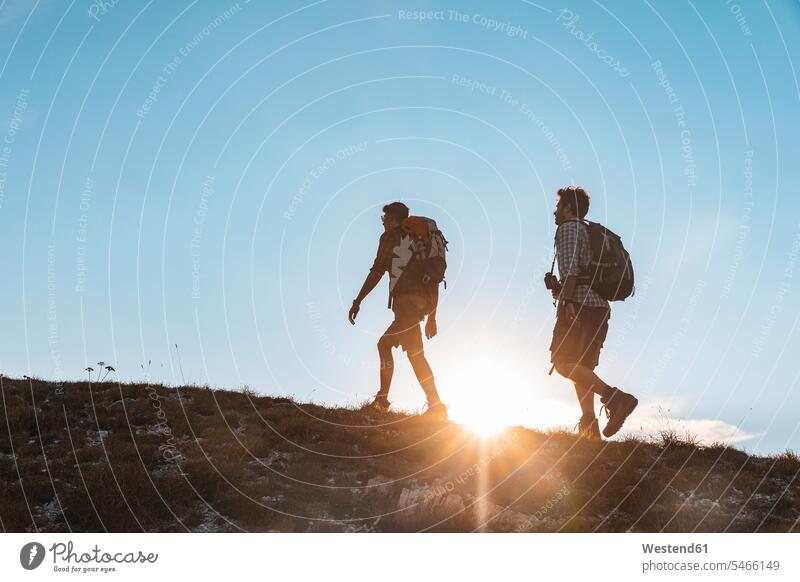 Italy, Monte Nerone, two men hiking in mountains at sunset sunsets sundown walking going man males hiker wanderers hikers mountain range mountain ranges