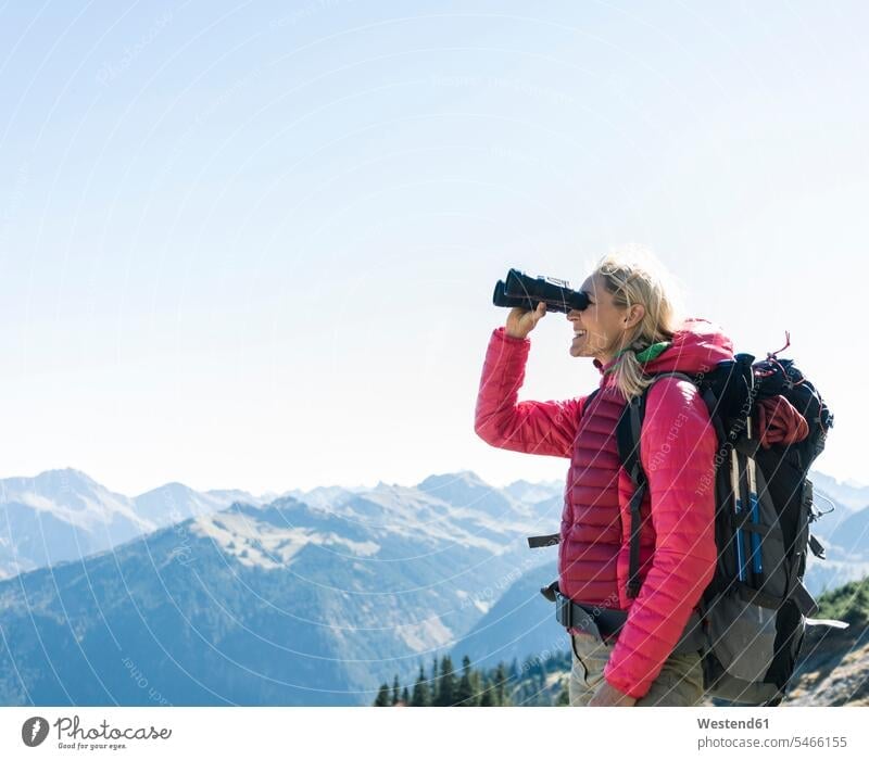 Austria, Tyrol, happy woman looking through binoculars during hiking trip happiness hiking tour walking tour females women hike view seeing viewing excursion