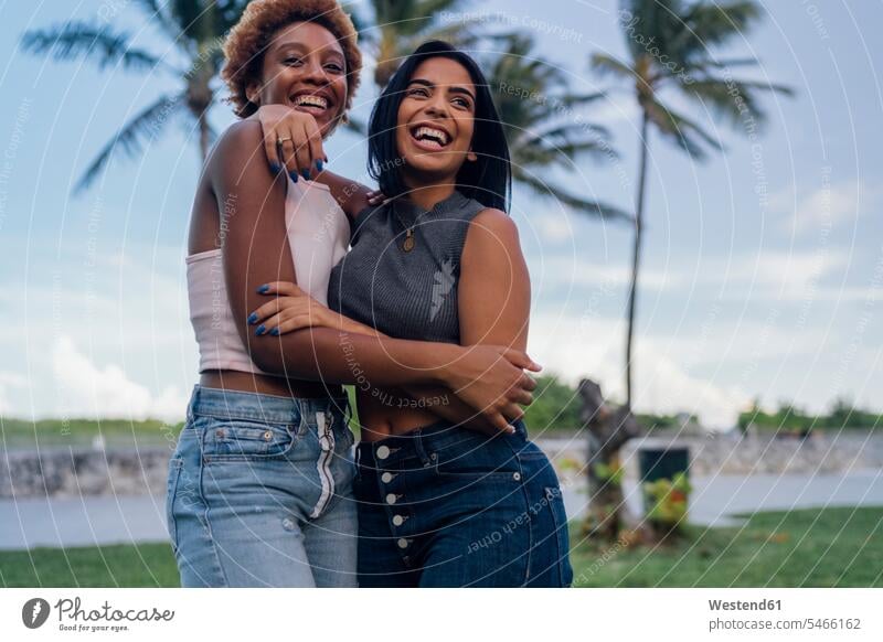 Two happy female friends hugging in a park embracing embrace Embracement parks happiness mate friendship cuddling female tourist beautiful Traveller Travellers
