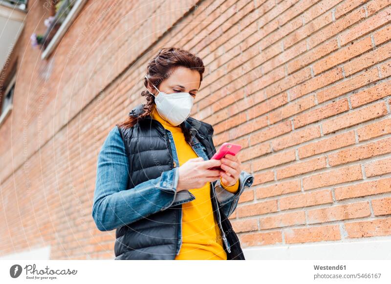 Woman covering her face with protective mask and using smartphone telecommunication phones telephone telephones cell phone cell phones Cellphone mobile