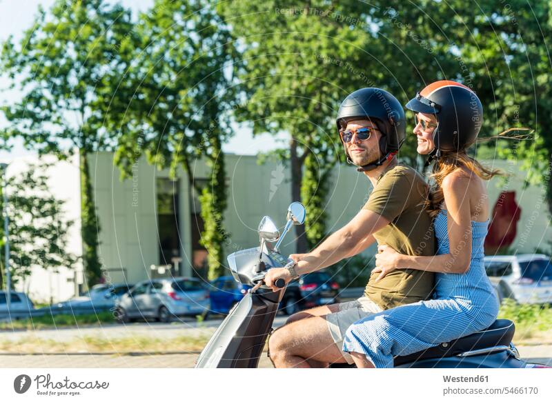Happy couple riding motor scooter in summer summer time summery summertime motor-scooter twosomes partnership couples happiness happy motor vehicle road vehicle