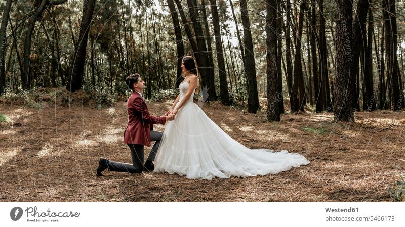 Man kneeling making a marriage proposal to happy bride in forest bridal couple bridal couples Wedding getting married marrying Marriage brides happiness groom
