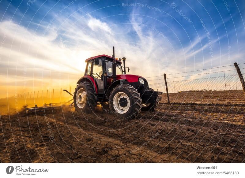 Man in tractor plowing agricultural land against cloudy sky color image colour image day daylight shot daylight shots day shots daytime outdoors location shots