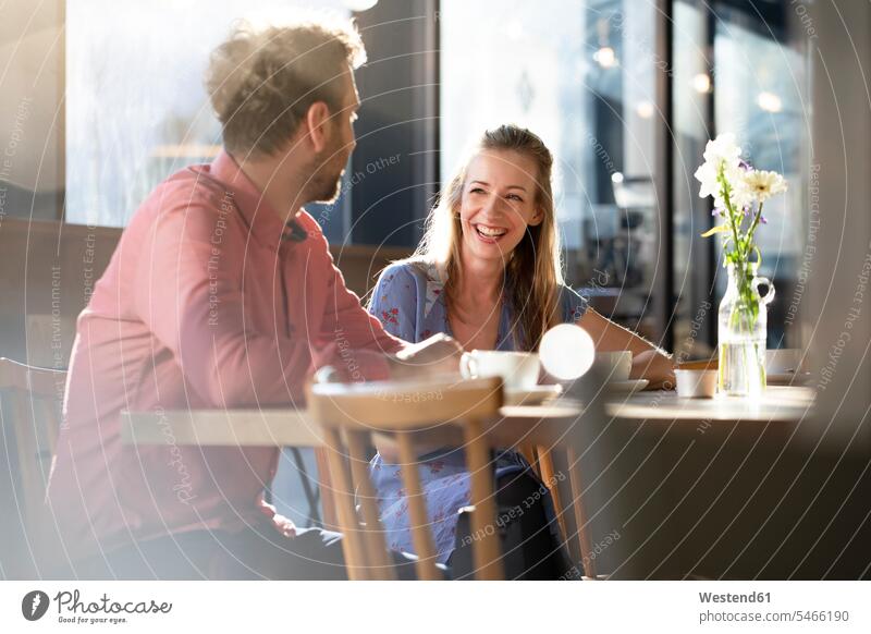 Laughing woman and man talking at table in a cafe windows Tables flirt Flirtation smile Seated sit speak speaking delight enjoyment Pleasant pleasure