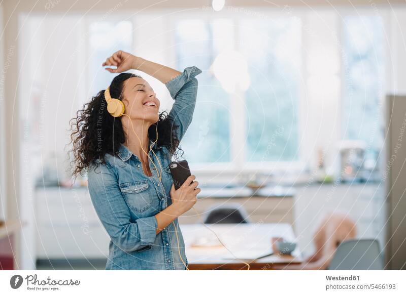 Happy woman listening music, singing and dancing, using smartphone and headphones human human being human beings humans person persons caucasian appearance