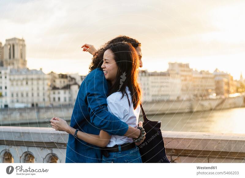 France, Paris, happy young couple hugging at river Seine at sunset happiness sunsets sundown twosomes partnership couples embracing embrace Embracement River