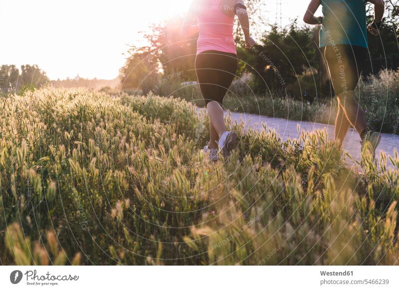 Active female athlete and sportsman jogging in park during sunset color image colour image outdoors location shots outdoor shot outdoor shots sunsets sundown