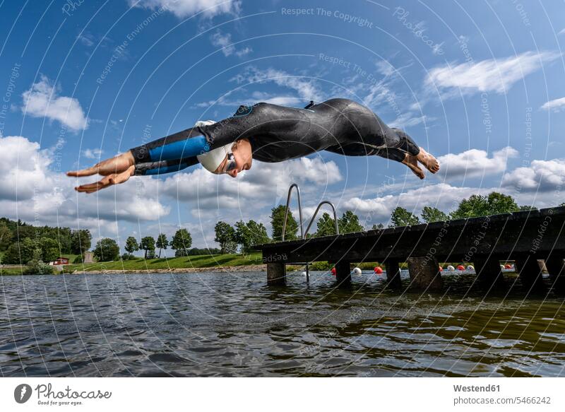 Young female triathlete jumping into a lake human human being human beings humans person persons caucasian appearance caucasian ethnicity european 1