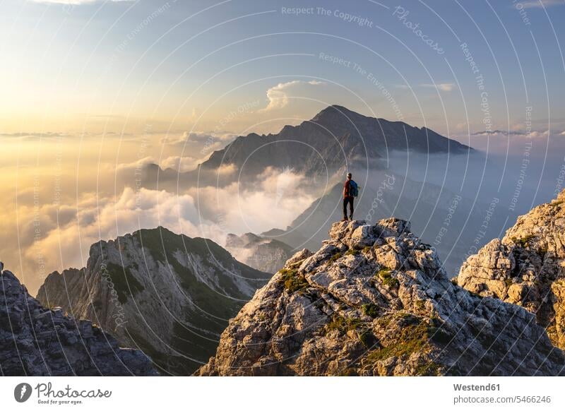 Hiker admiring awesome view while standing on mountain peak at Bergamasque Alps, Italy color image colour image outdoors location shots outdoor shot