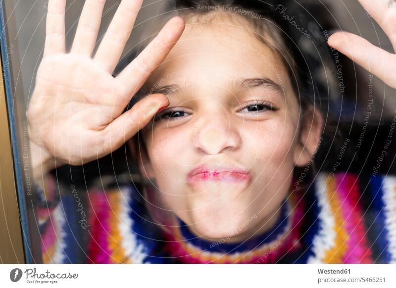 Portrait of happy playful girl in striped pullover behind windowpane happiness stripes portrait portraits females girls window glass window glasses windowpanes