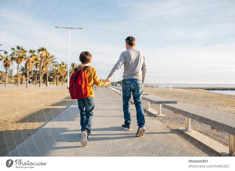 Father and son walking on beach promenade father pa fathers daddy dads papa beaches sons manchild manchildren going promenades parents family families people
