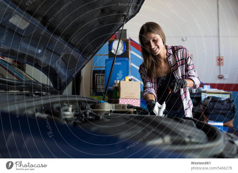 Young casual woman in shirt and gloves working with car in repair service checking engine oil level human human being human beings humans person persons