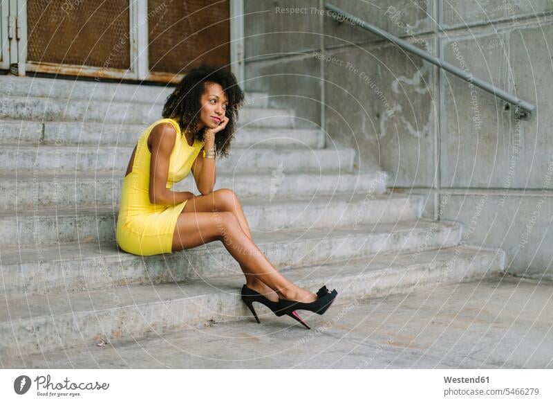 Fashionable businesswoman in yellow dress and high heels sitting on stairs businesswomen business woman business women fashionable high heeled shoes