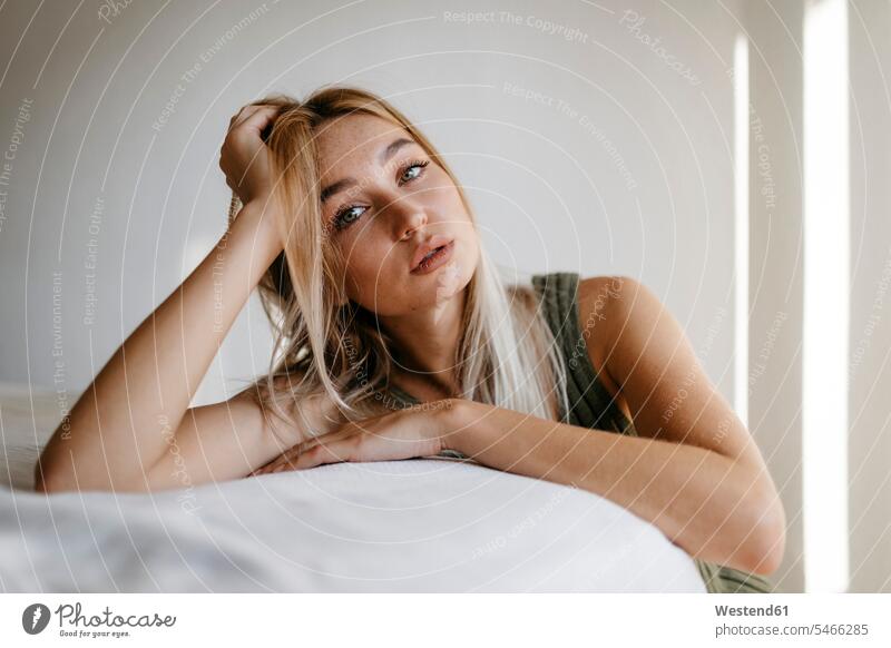 Seductive young woman with hand in hair leaning bed at home color image colour image indoors indoor shot indoor shots interior interior view Interiors day