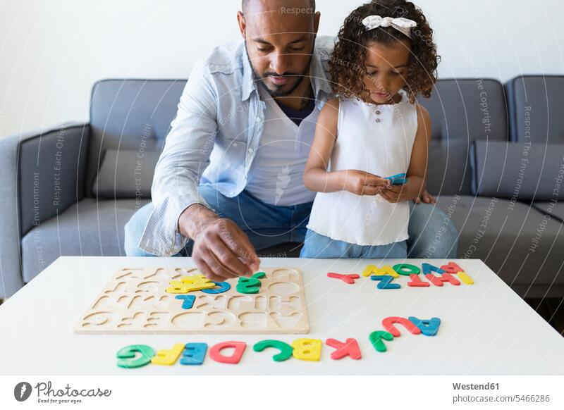 Father and daughter playing with alphabet learning game at home human human being human beings humans person persons Mixed Race mixed race ethnicity