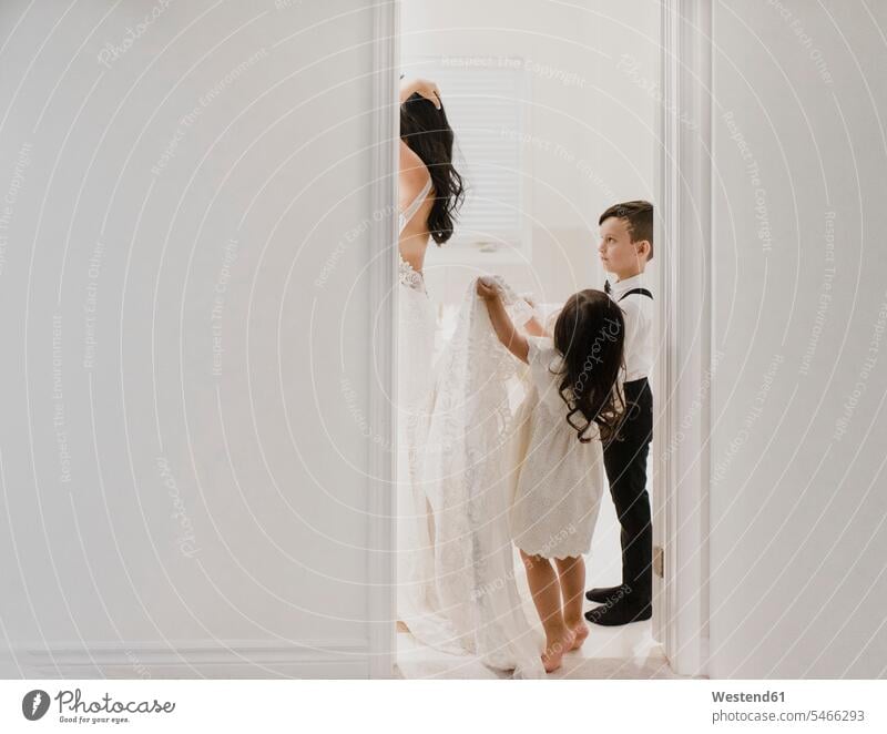 Daughter holding dress while son looking at mother getting ready for wedding in bathroom color image colour image indoors indoor shot indoor shots interior