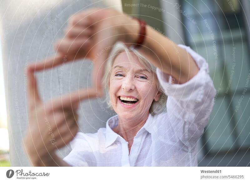 Portrait of laughing mature woman shaping frame with her fingers delight enjoyment Pleasant pleasure happy colour colours Attractiveness beautiful good-looking