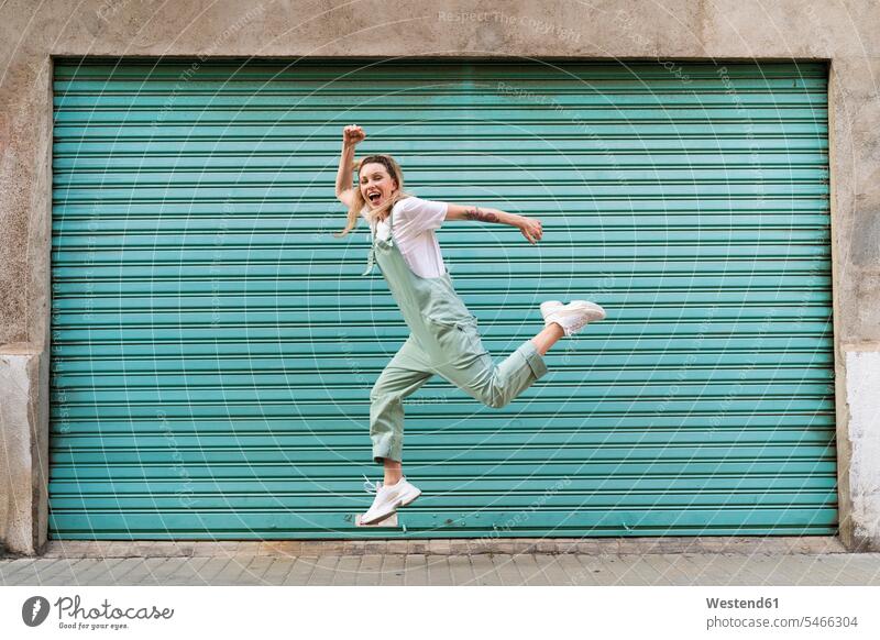 Happy young woman jumping for joy in the city jumps Leaping delight enjoyment Pleasant pleasure Cheerfulness exhilaration gaiety gay glad Joyous merry happy