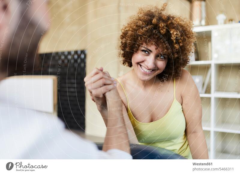 Happy man and woman arm wrestling in office Germany Selective focus Differential Focus employee employess Female Colleague playful competition competing