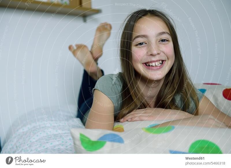 Portrait of laughing girl lying on bed laying down lie lying down beds portrait portraits females girls Laughter child children kid kids people persons