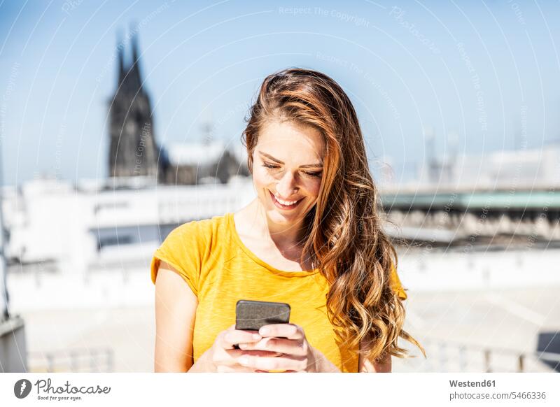 Germany, Cologne, smiling woman using cell phone females women smile Smartphone iPhone Smartphones use Adults grown-ups grownups adult people persons