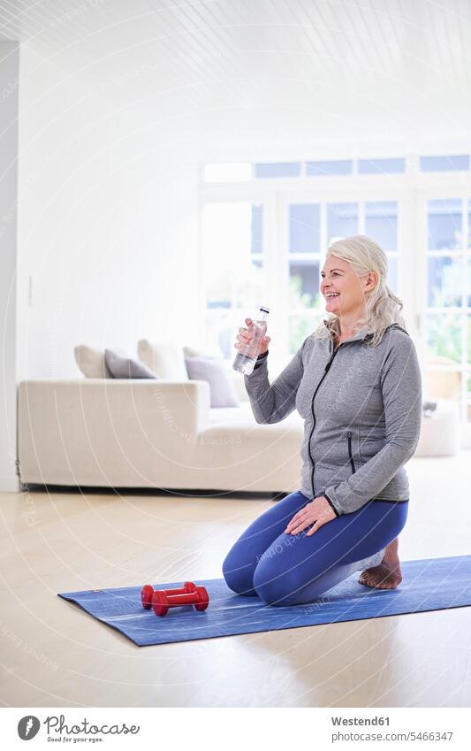 Smiling woman having water while exercising with dumbbells in living room color image colour image indoors indoor shot indoor shots interior interior view