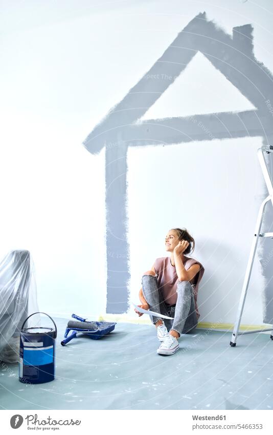 Young woman holding paper while sitting against house painted on wall at home color image colour image indoors indoor shot indoor shots interior interior view