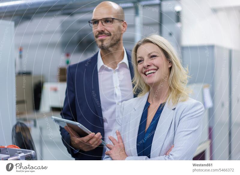 Cheerful businesswoman standing by colleague while looking away in factory color image colour image indoors indoor shot indoor shots interior interior view