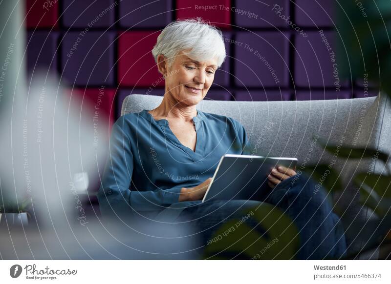 Portrait of senior businesswoman sitting on lounge chair using digital tablet business life business world business person businesspeople business woman