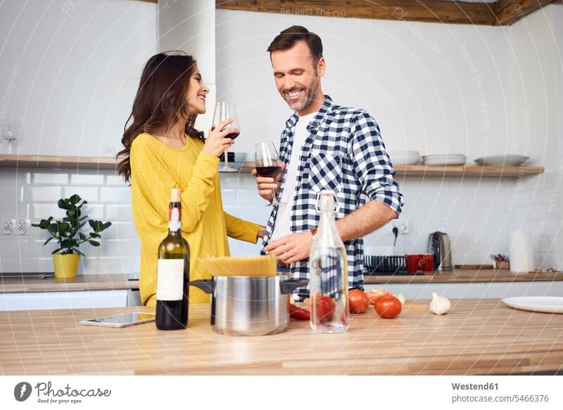 Affectionate couple in kitchen, preparing spaghetti toghether, drinking red wein Red Wine Red Wines cooking smiling smile twosomes partnership couples