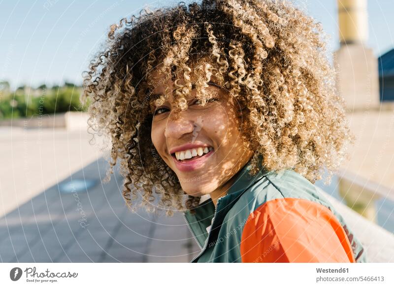 Happy young woman with curly hair during sunny day color image colour image outdoors location shots outdoor shot outdoor shots daylight shot daylight shots