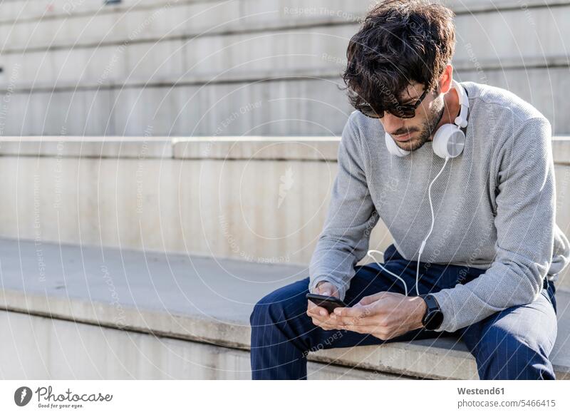 Man sitting on outdoor stairs using smartphone human human being human beings humans person persons caucasian appearance caucasian ethnicity european 1