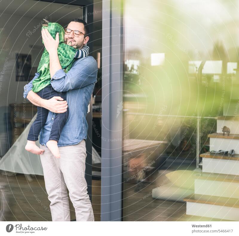 Affectionate father carrying son in a costume at terrace door at home patio door French window fancy dress fancy-dress costume Fancy Dress Costumes disguise