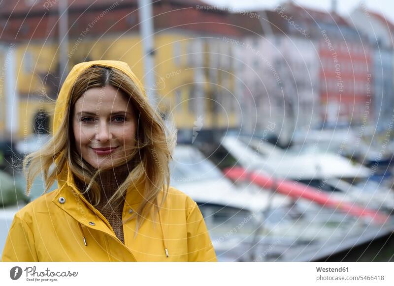Denmark, Copenhagen, portrait of smiling woman at city harbour in rainy weather town cities towns females women portraits smile outdoors outdoor shots