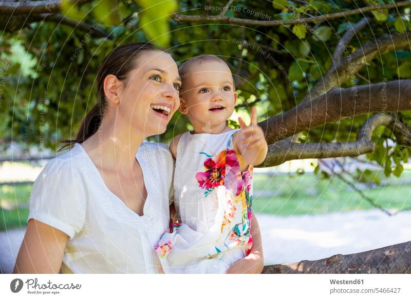Happy mother and little daughter under a tree discovering something mommy mothers ma mummy mama happiness happy daughters Tree Trees parents family families