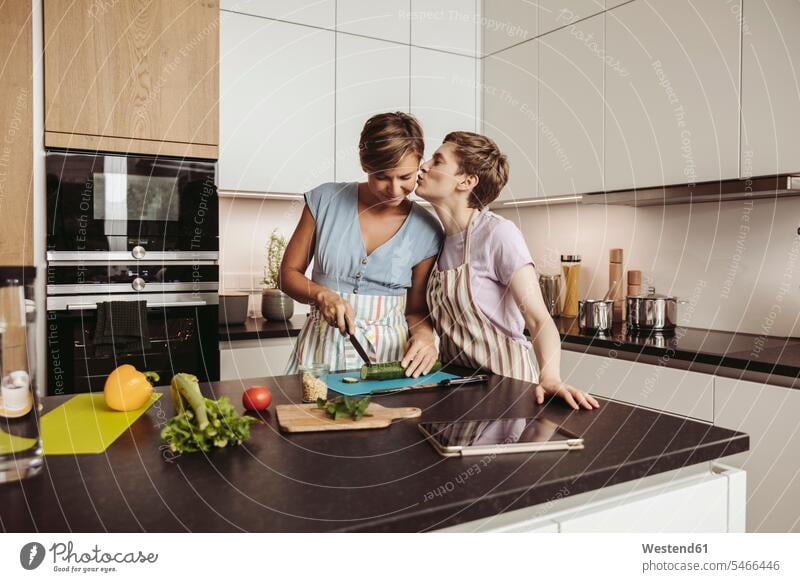 Happy lesbian couple in kitchen cooking together twosomes partnership couples happiness happy people persons human being humans human beings homosexual woman