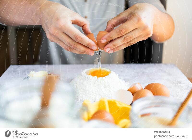 Hands of woman breaking egg into flour heap Raw Food women female females female adult female adults foods kitchen caucasian caucasian appearance
