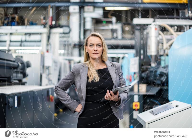 Portrait of confident woman holding tablet in factory shop floor portrait portraits confidence industrial hall factory hall industrial buildings females women