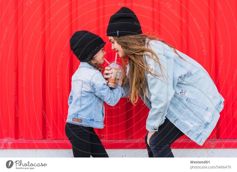 Teenage girl and little sister having fun together Spain denim jacket jeans jackets woolly hat Wooly Hat Knit-Hat Knit Hats wool cap blowing hair windswept