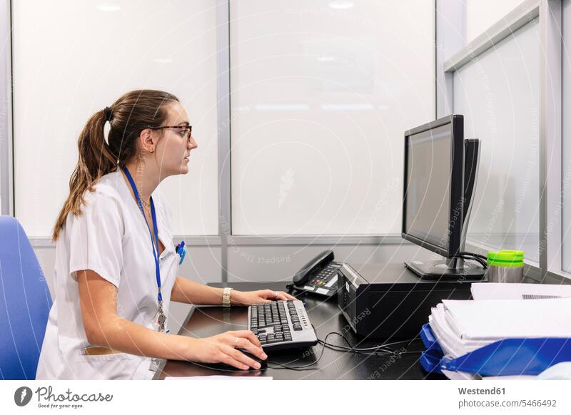 Female pharmacist using computer on desk in pharmacy color image colour image Spain indoors indoor shot indoor shots interior interior view Interiors