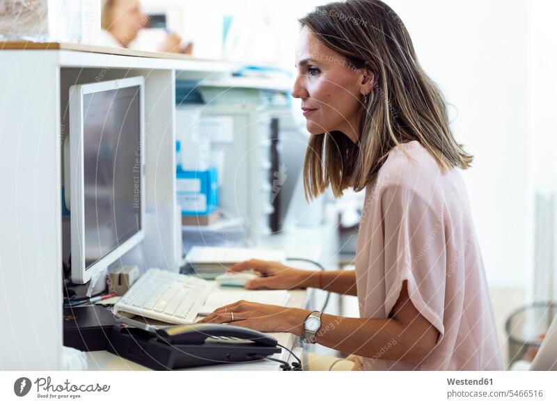 Woman working on computer at reception desk human human being human beings humans person persons caucasian appearance caucasian ethnicity european 2 2 people